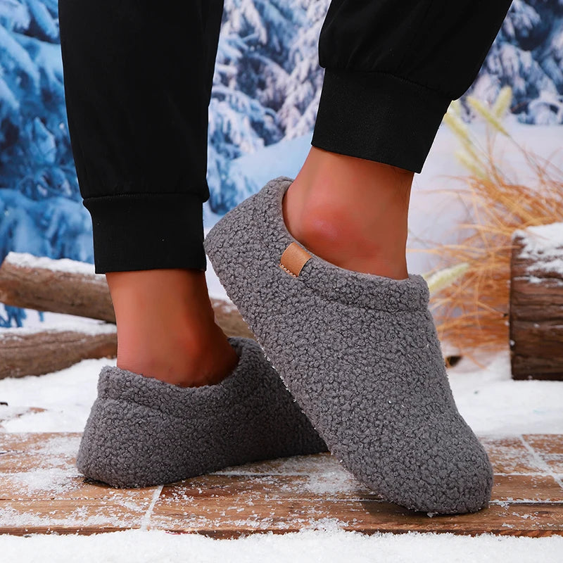 A person mid-step wearing gray teddy fleece slides, one foot lifted, on a snowy wooden bench outdoors.