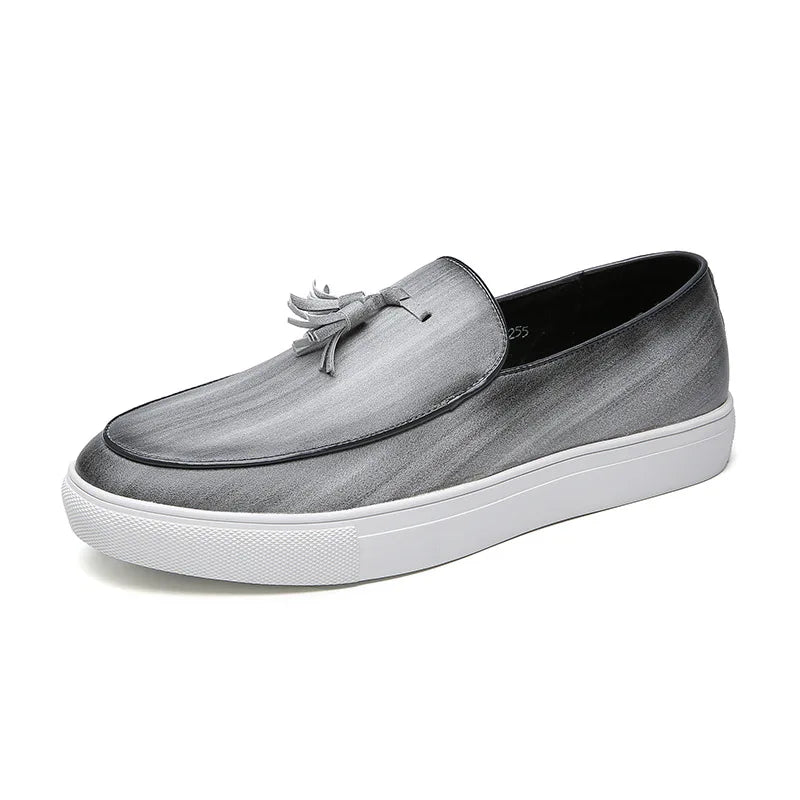 A gray leather tassel loafer with a white sole, shown in side profile on a plain white background.