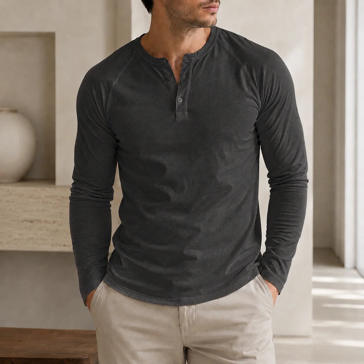 Man wearing a charcoal gray long-sleeve Henley sweater with a three-button neckline and classic fit.
