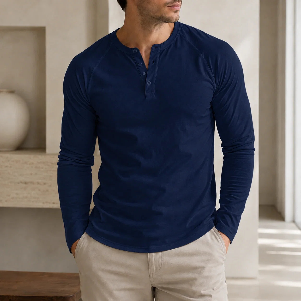 Man wearing a navy blue long-sleeve Henley sweater with a three-button placket, ribbed cuffs, and a classic slim fit.