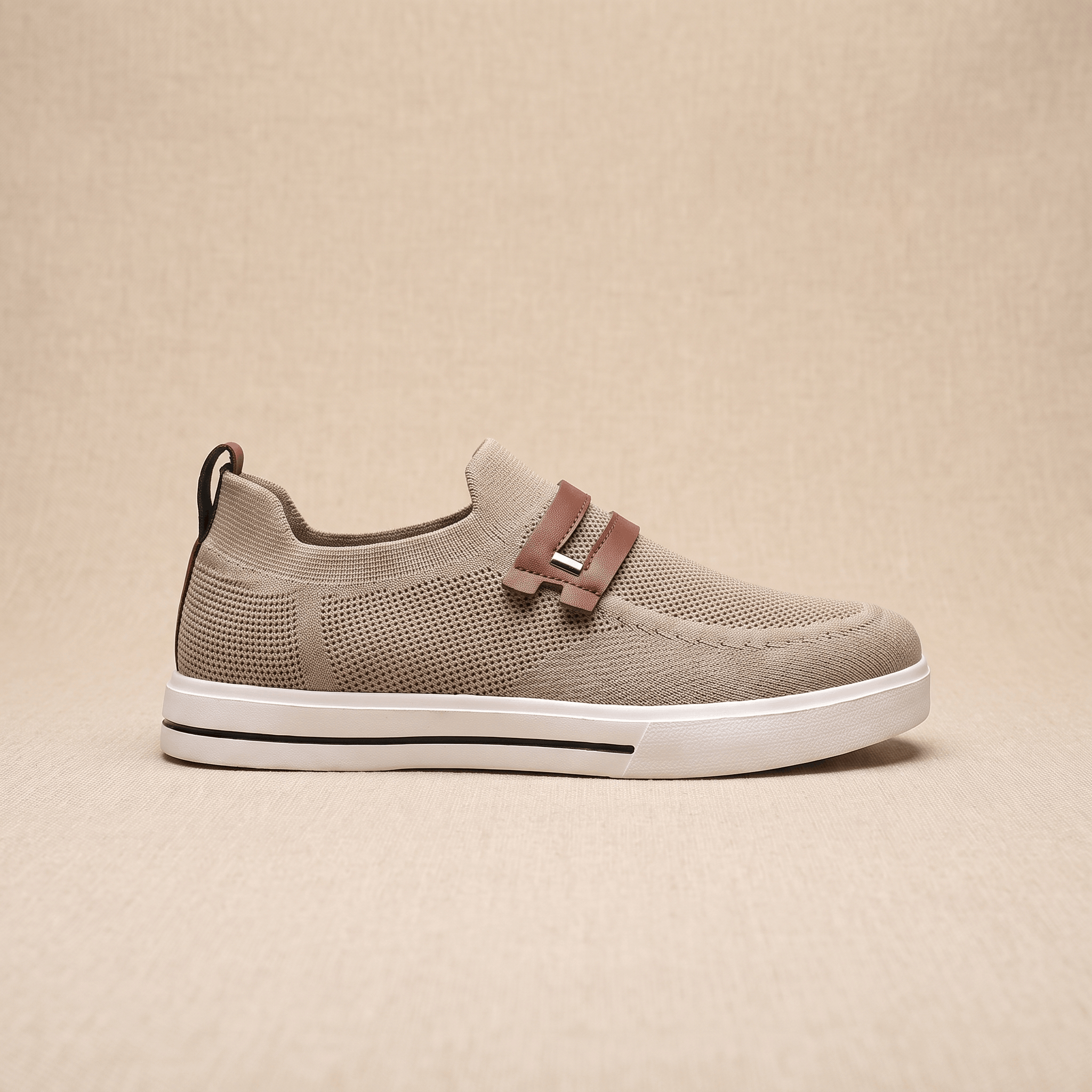 Side profile of a single khaki mesh Orion sneaker with brown leather strap, resting on a beige surface