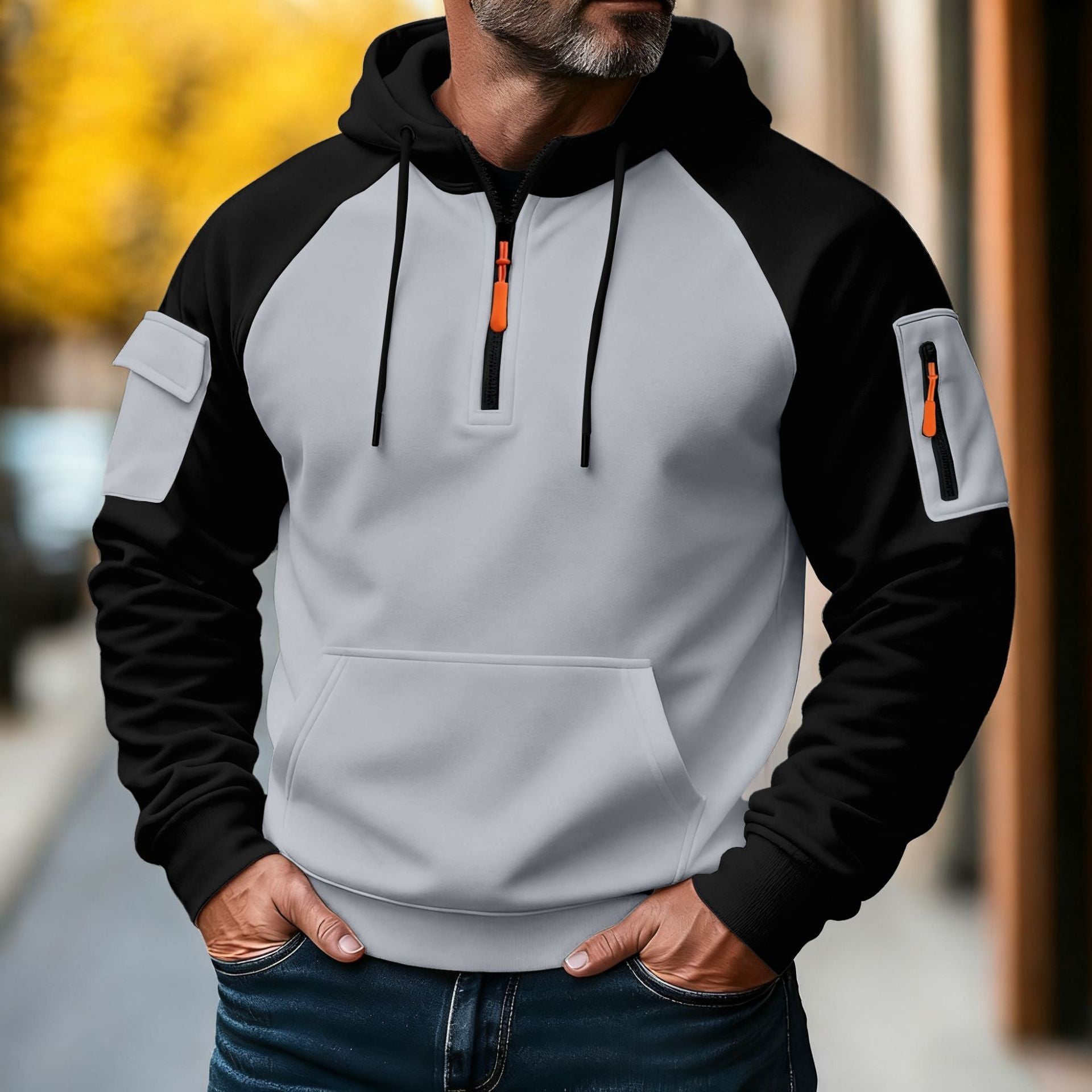 Man wearing a white and black color-block tactical hoodie featuring a half-zip closure, adjustable hood, sleeve utility pocket, and kangaroo pocket.