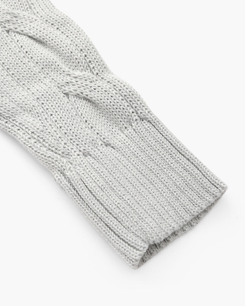 Close-up of a light gray cable knit sweater sleeve highlighting the textured knit and ribbed cuff.
