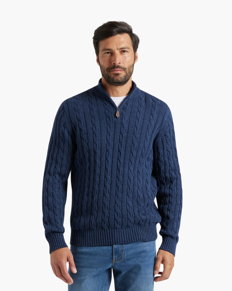 Navy cable knit quarter-zip sweater with a stand collar and ribbed cuffs, worn with blue jeans on a white background.