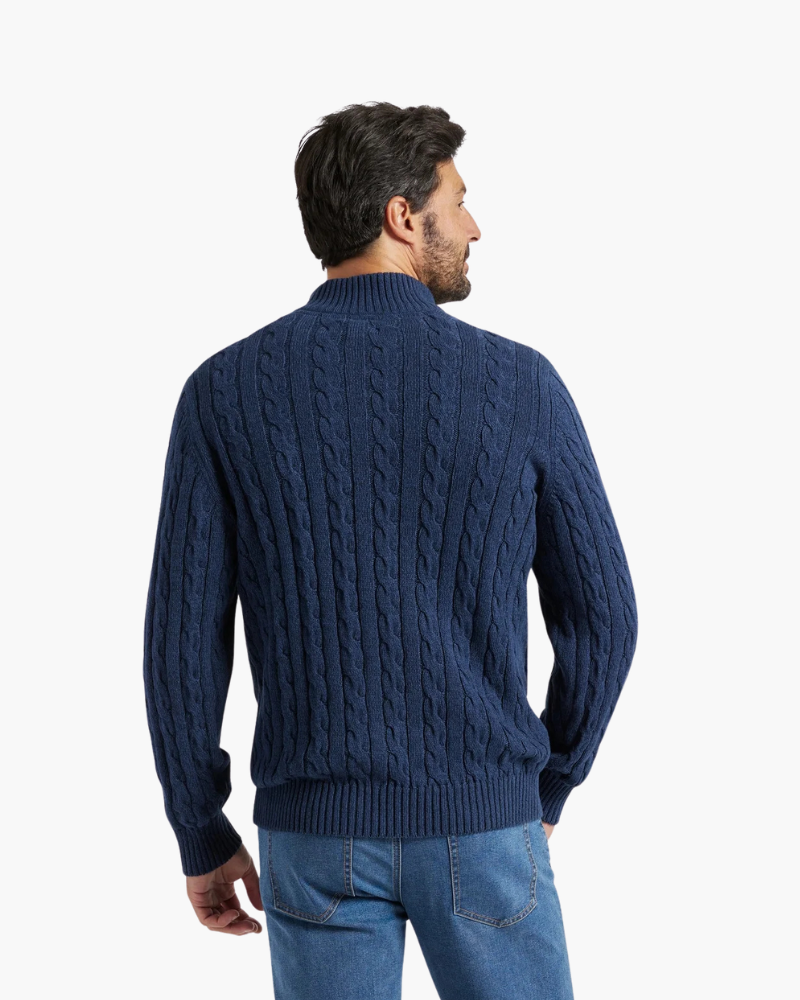 Back view of a navy cable knit quarter-zip sweater with a stand collar, paired with blue jeans.