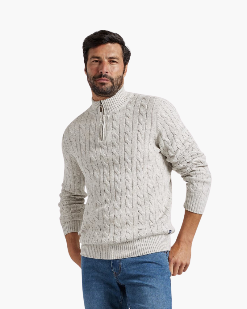 Light gray cable knit quarter-zip sweater with a stand collar and ribbed cuffs, worn with blue jeans on a white background.
