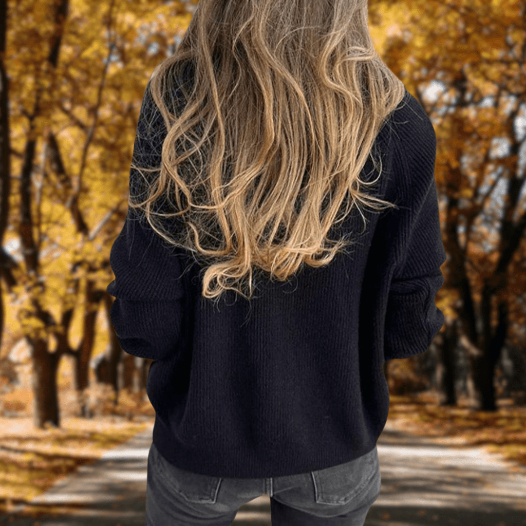 Back view of a woman wearing a navy ribbed quarter-zip knit sweater with a high collar and long sleeves.