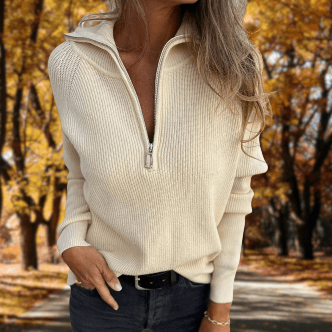 Woman wearing a cream ribbed quarter-zip knit sweater with a high collar, long sleeves, and a relaxed fit outdoors in an autumn setting.
