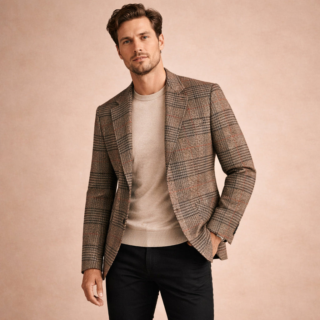 Man wearing a brown plaid tweed blazer with a notched lapel, two-button closure, and tailored fit over a beige crew neck sweater and black trousers.