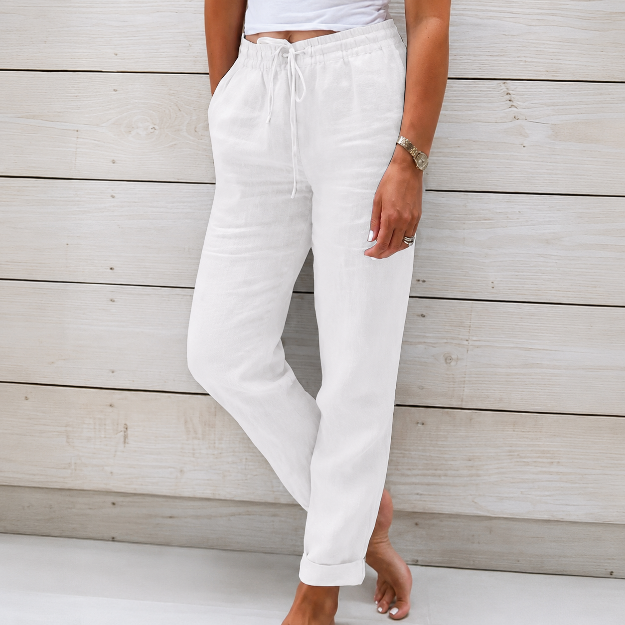 Women's white linen drawstring pants with a relaxed tapered leg, elastic waistband, and side pockets.