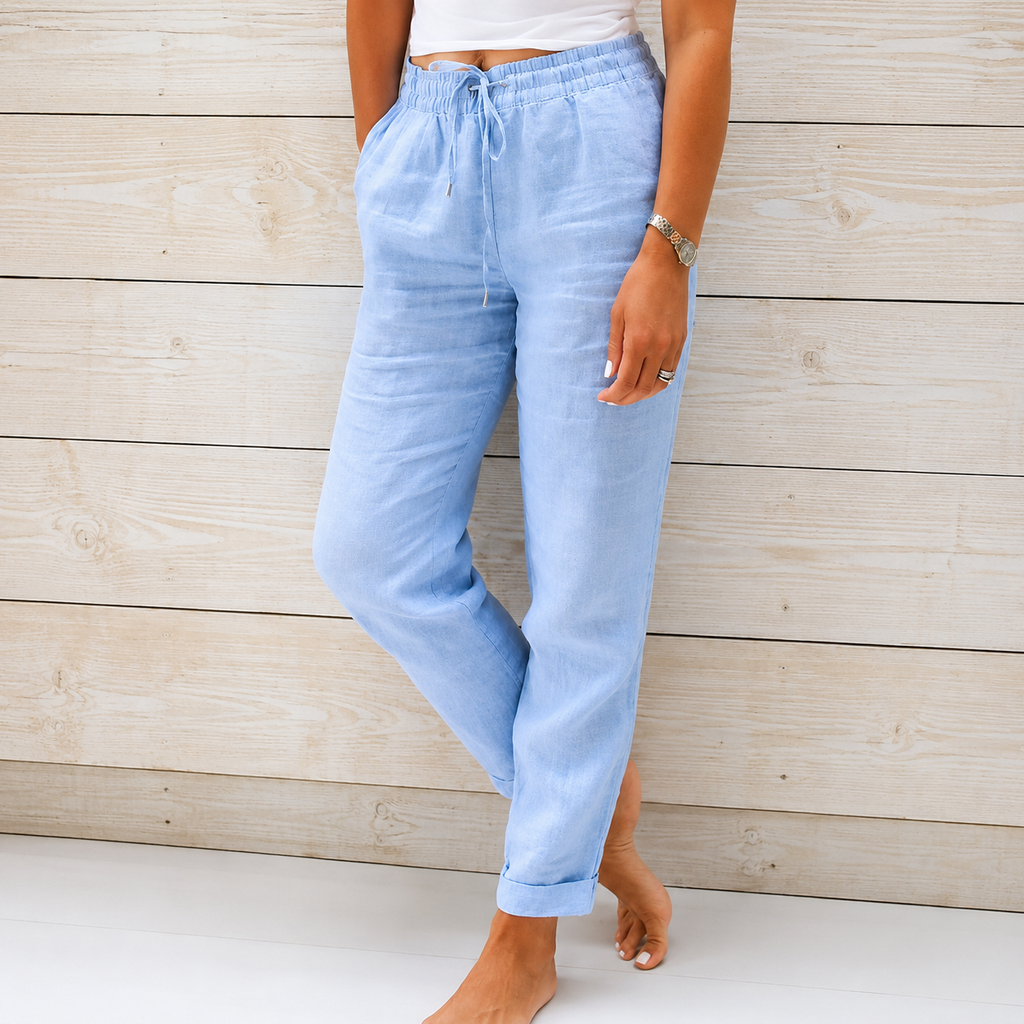 Women's light blue linen drawstring pants with a relaxed tapered fit, elastic waistband, and side pockets.