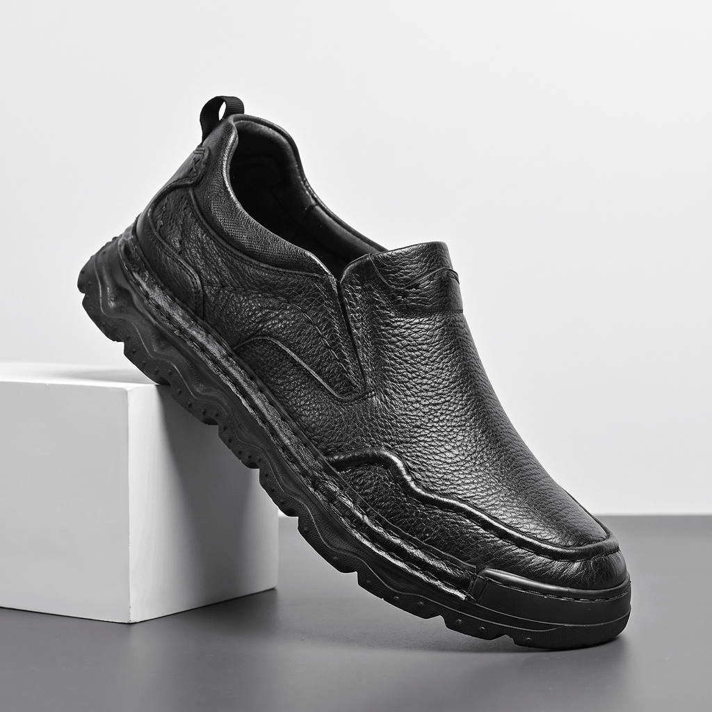 Side view of a single black leather Piolo loafer propped against a white block, showing chunky sole and pull tab
