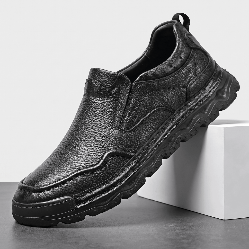 Single black leather Piolo slip-on loafer with pull tab and chunky sole, angled on a white block against a studio backdrop