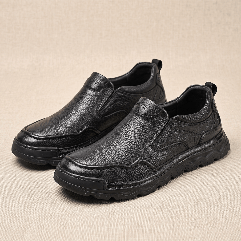 Pair of black leather Piolo slip-on loafers, resting on a beige fabric backdrop