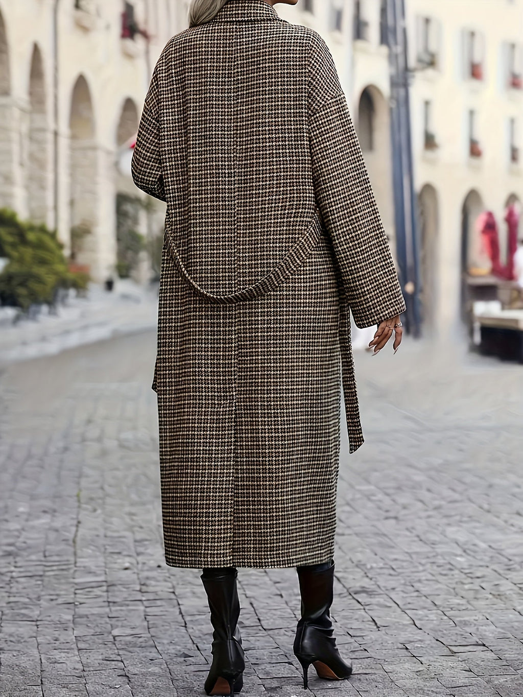 Longline plaid trench coat in a structured H-line silhouette with a belted waist, worn over black heeled boots.