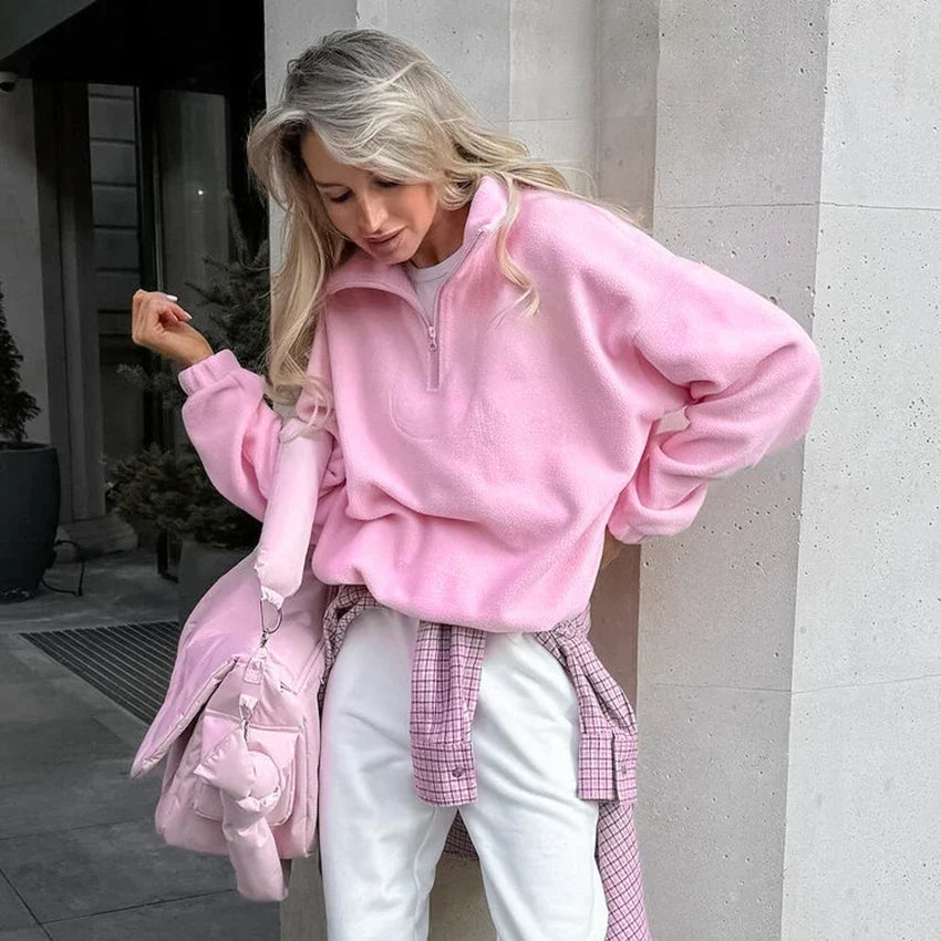 Pink quarter-zip fleece pullover worn by a female model in a seated pose
