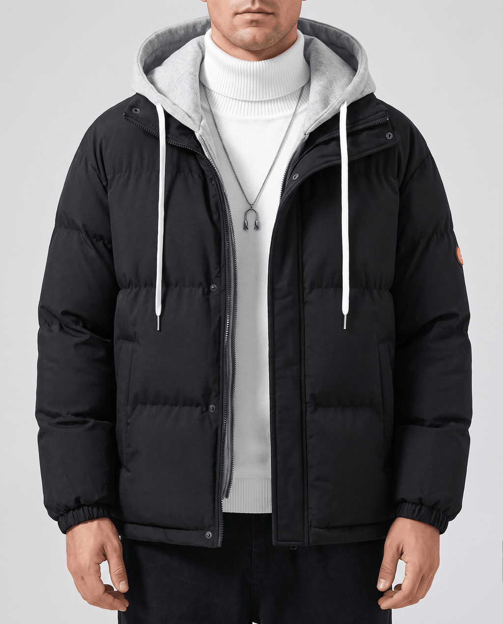 A man wearing a black quilted hooded puffer jacket with drawstring hood and zip pockets