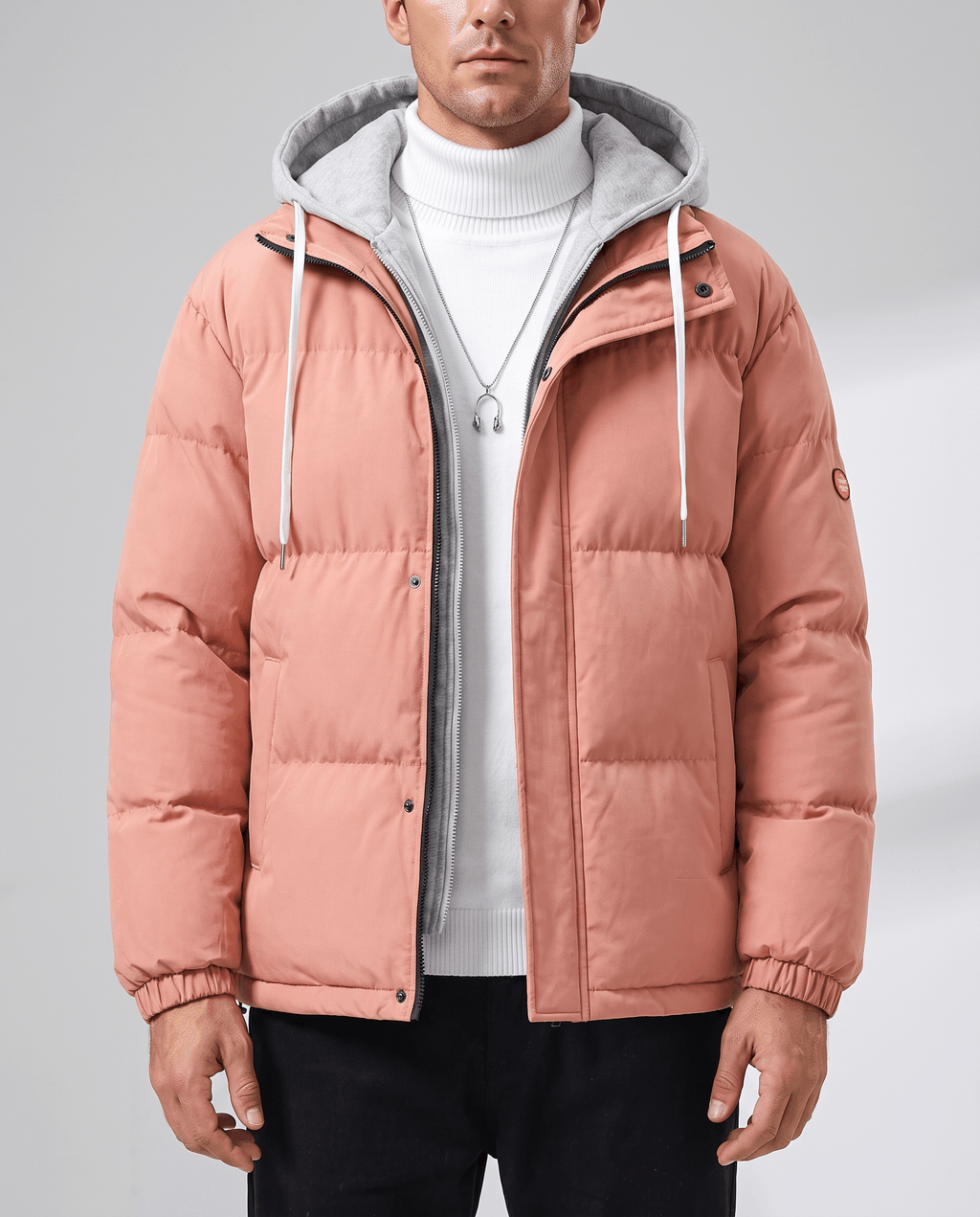 A man wearing a pink quilted hooded puffer jacket with drawstring hood and zip pockets