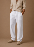 Man wearing light gray linen drawstring pants with a relaxed straight-leg fit and elastic waistband.