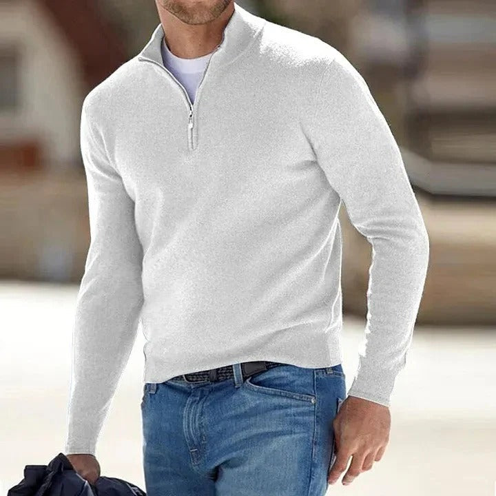 White half-zip knit sweater featuring a stand collar and long sleeves, worn with blue jeans outdoors.