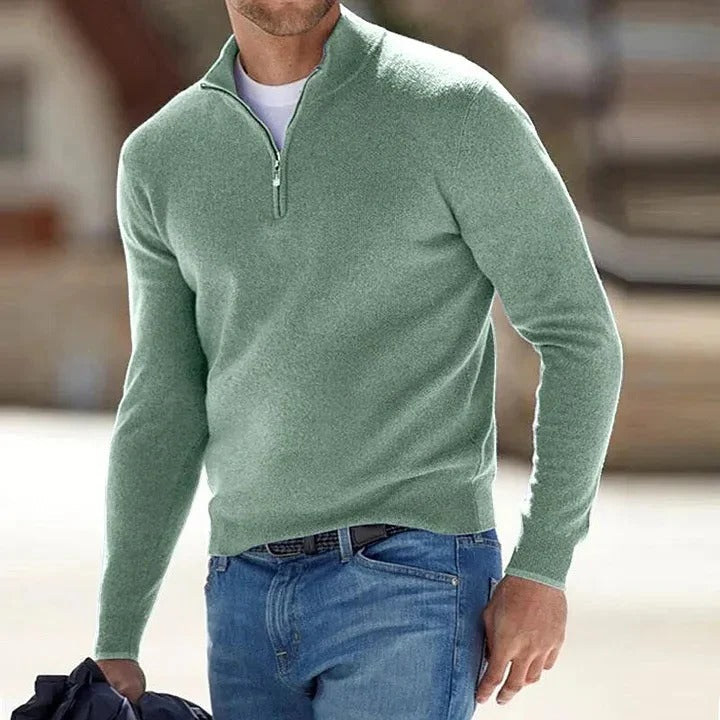 Green half-zip knit sweater with a stand collar and long sleeves, paired with blue jeans in a casual outdoor setting.