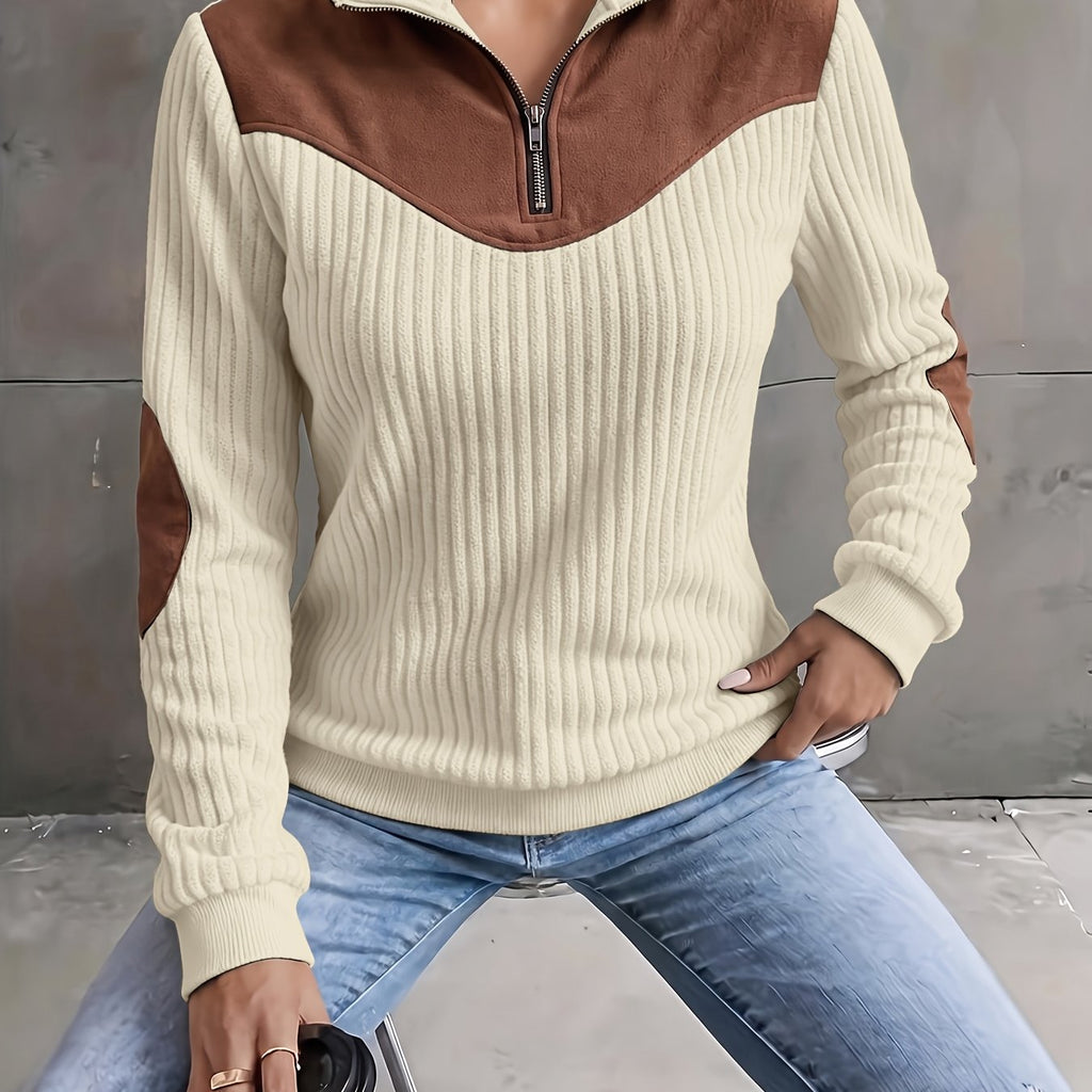 Cream ribbed knit quarter-zip sweater with brown suede-look yoke and elbow patches worn with blue jeans.