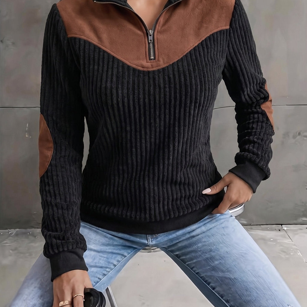 Black ribbed knit quarter-zip sweater with brown suede-look yoke and elbow patches, styled with light wash jeans.