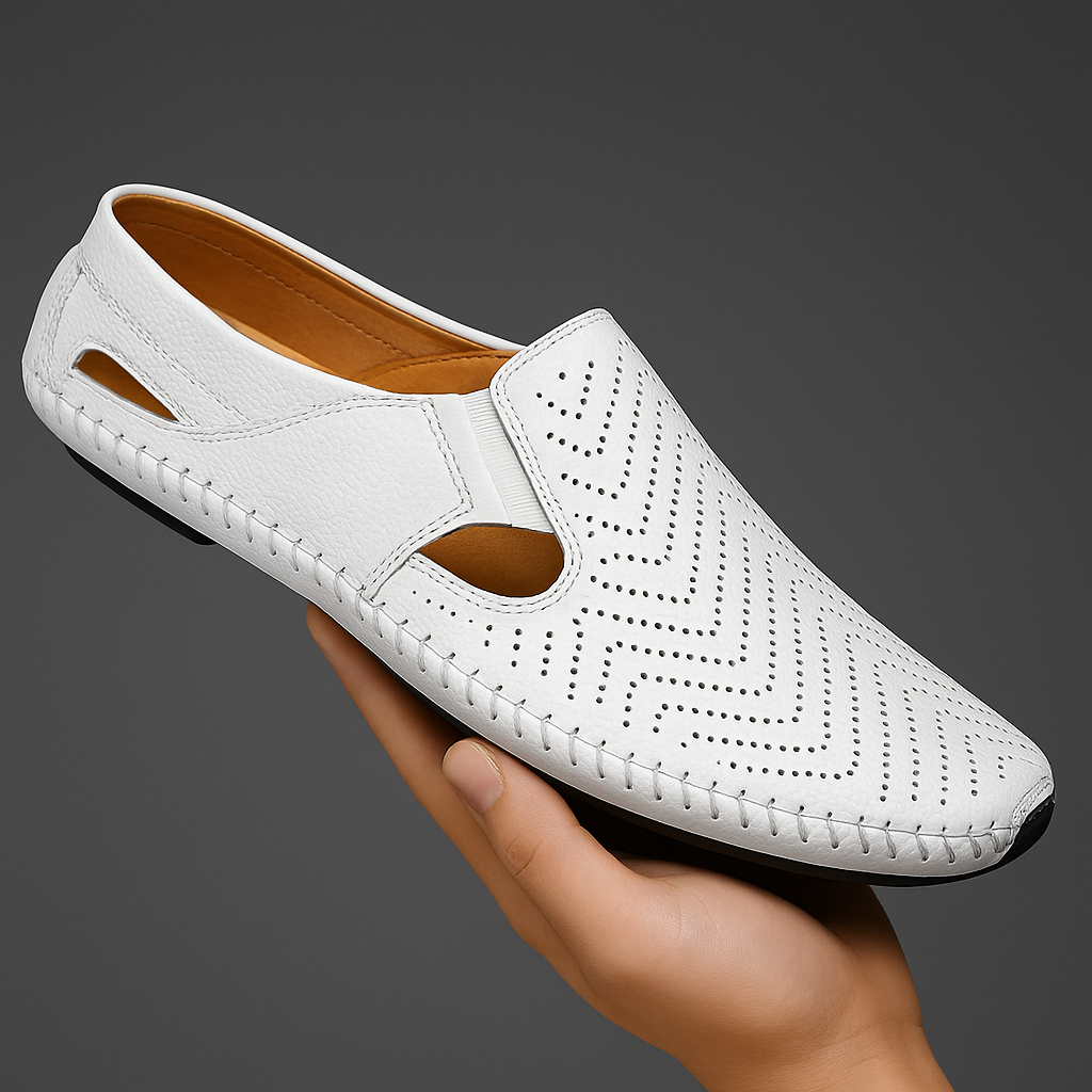 Hand holding a white perforated leather slip-on sandal with a chevron-pattern texture and hand-stitched trim.