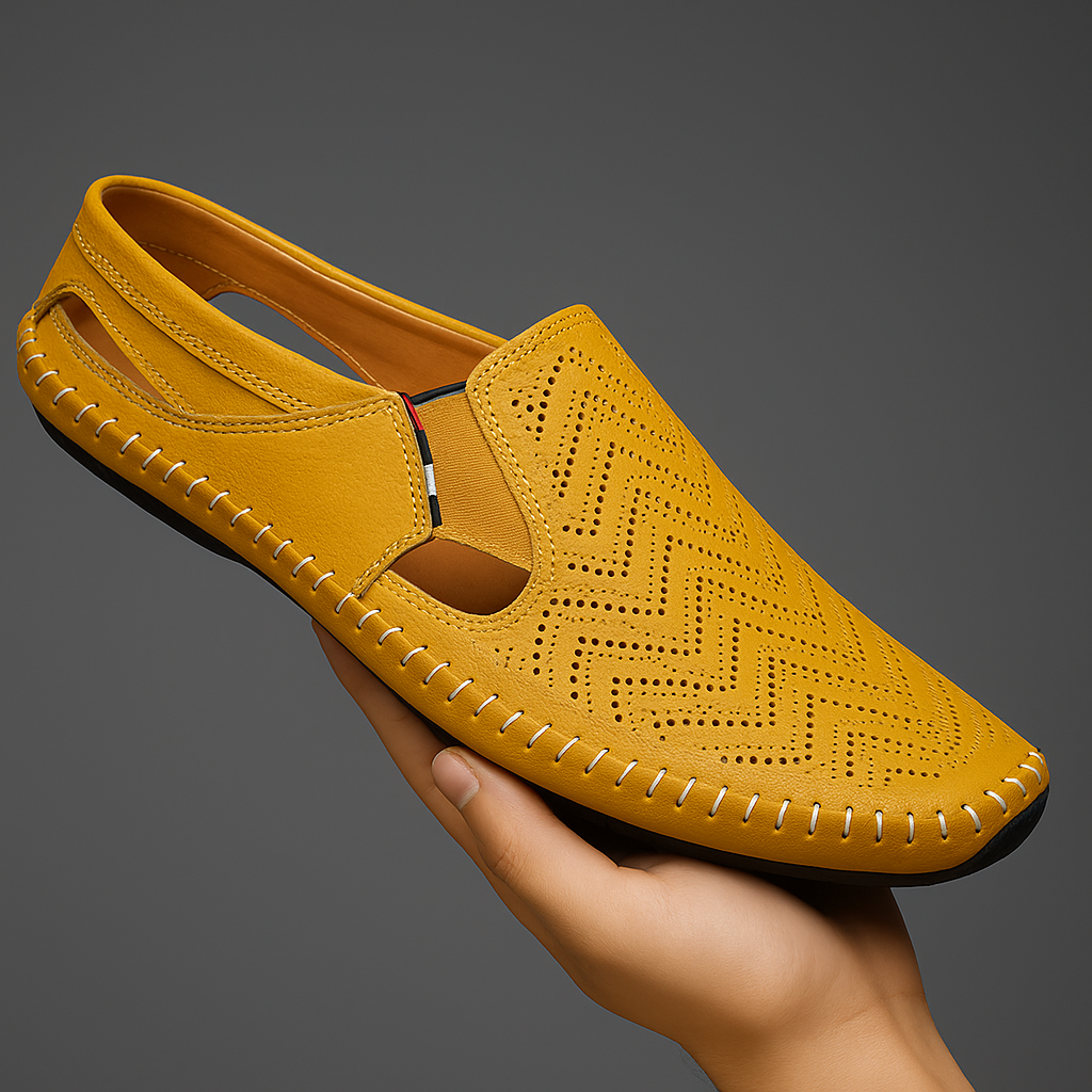 Hand holding a yellow perforated leather slip-on sandal with a chevron-pattern texture and hand-stitched trim.