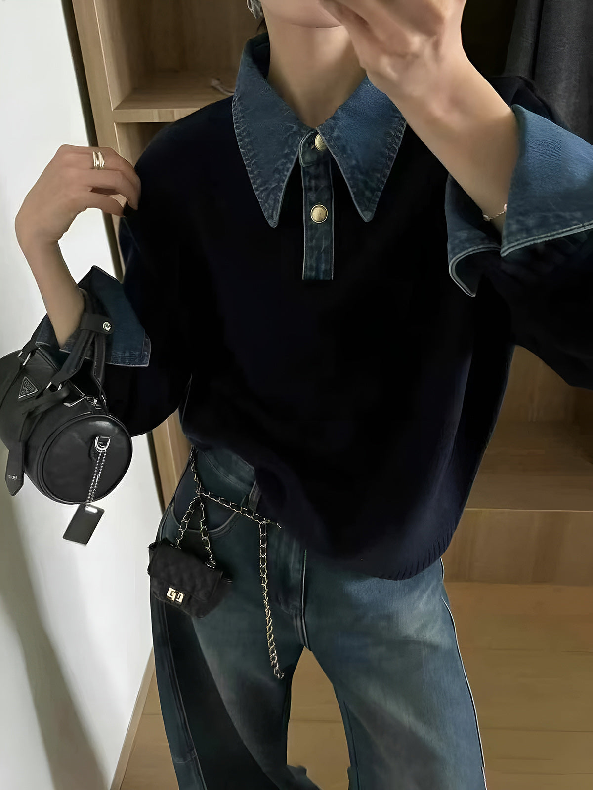 Woman wearing a navy knit sweater featuring a denim collar and cuffs, styled with blue jeans and carrying a shoulder bag.