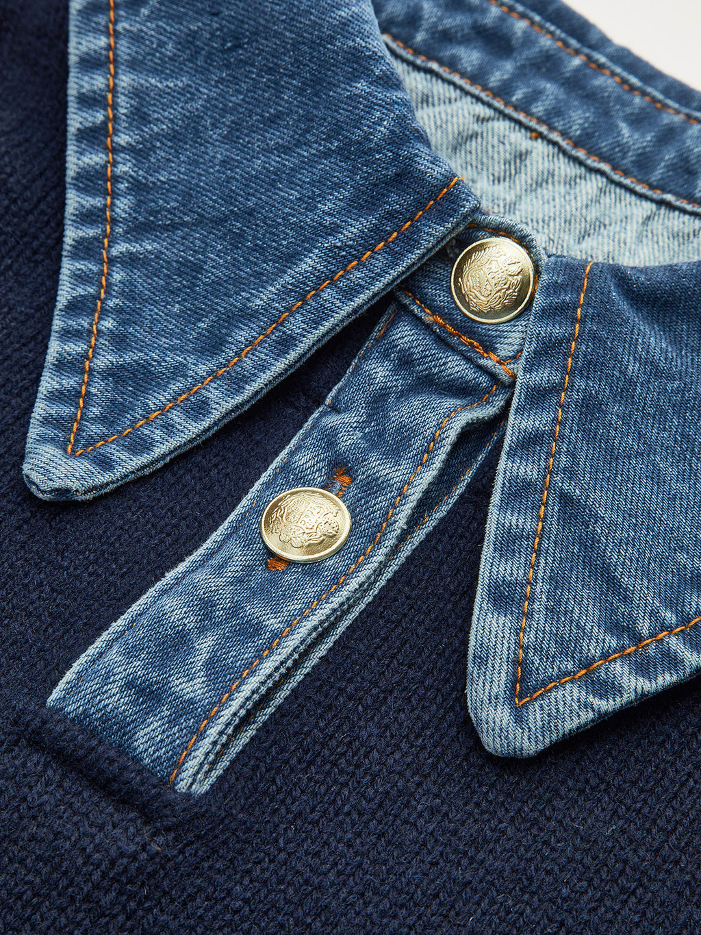 Close-up of the sweater's denim shirt collar with snap buttons and contrast stitching.