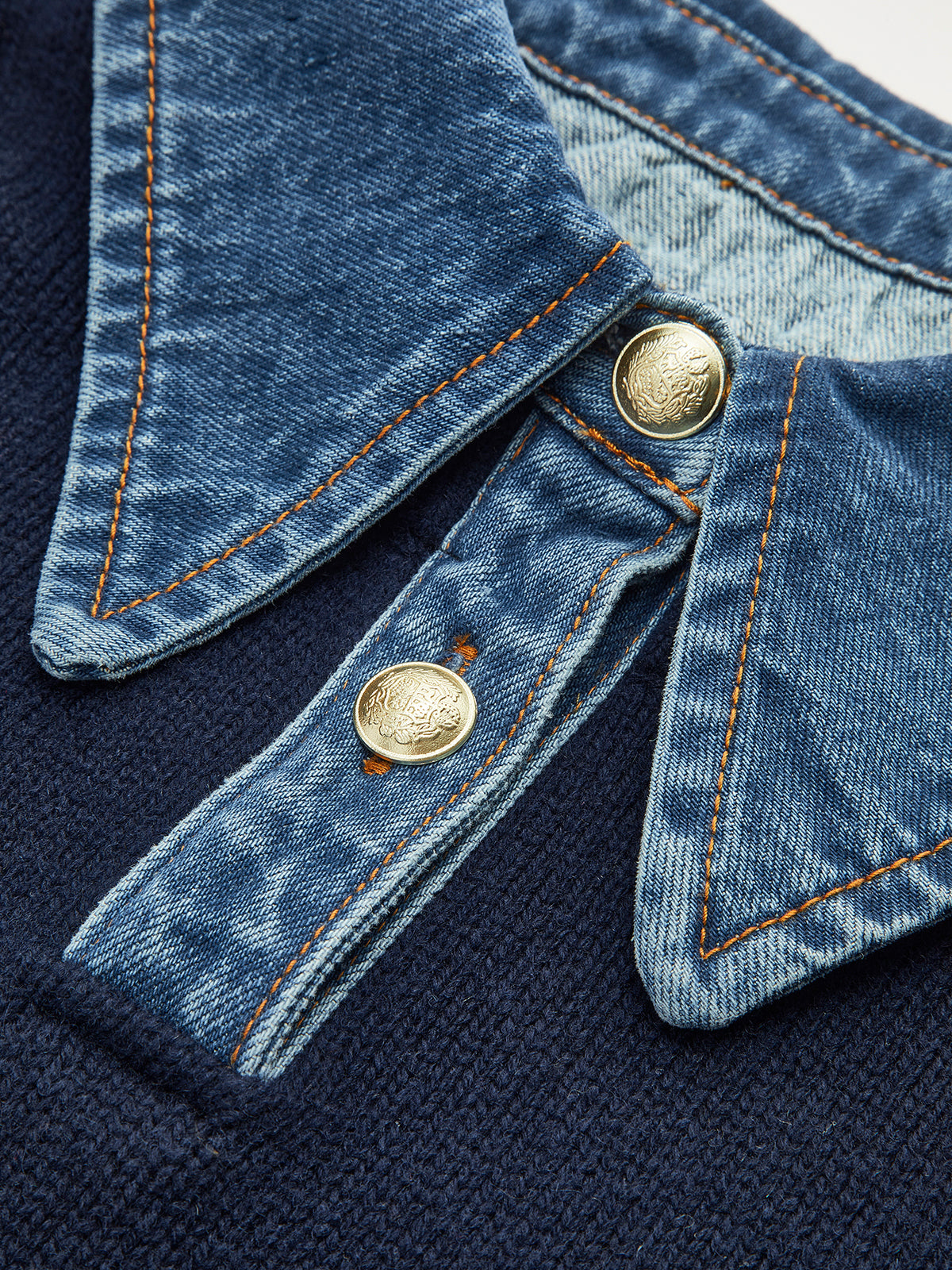 Close-up of the sweater's denim shirt collar with snap buttons and contrast stitching.