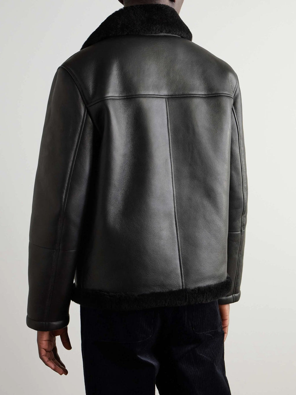 Black leather aviator jacket with plush shearling collar and hem, featuring structured panel construction.