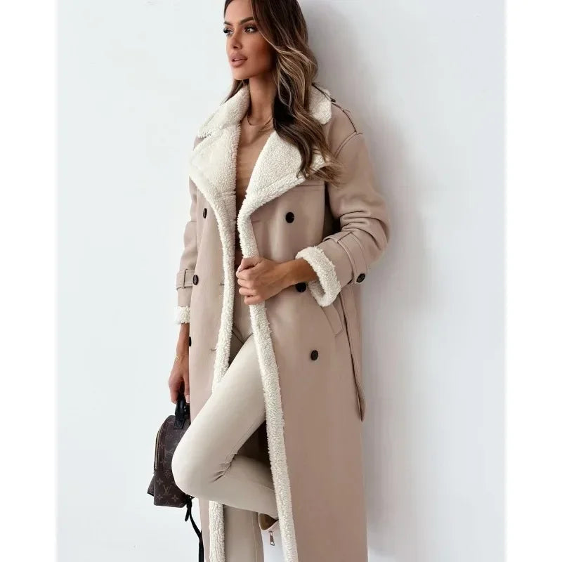 Beige shearling trench coat with cream teddy lining, double-breasted buttons, and a belted waist in a longline fit.