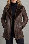 Brown vegan leather jacket with a plush shearling collar, tailored fit, and full zip front worn over a black turtleneck.