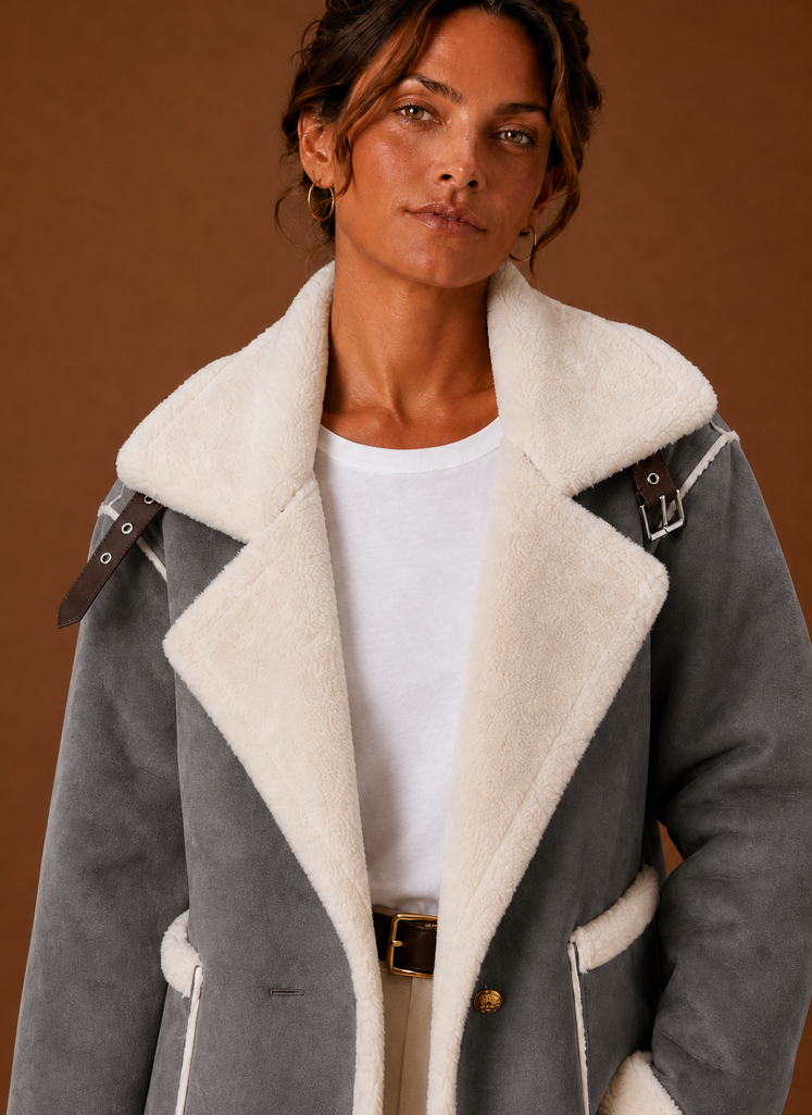 Grey suede-look aviator jacket with wide sherpa lapels, buckled shoulder straps, and plush white fleece trim.