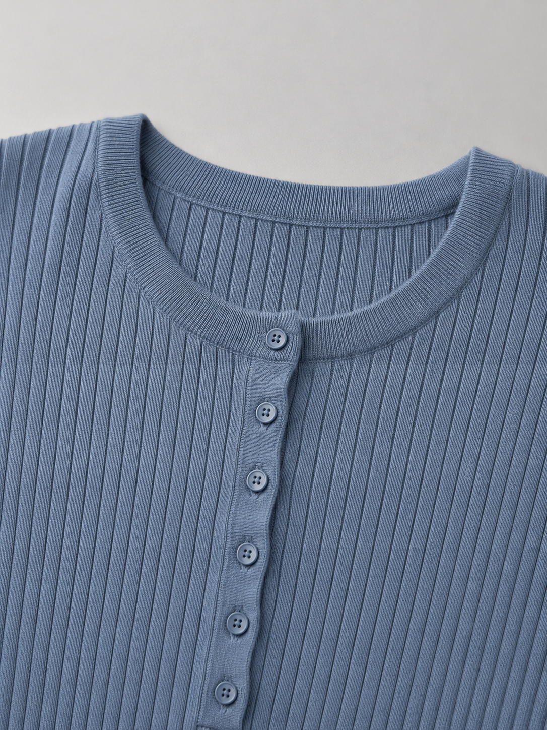 Close-up of the blue ribbed knit sweater showcasing the button-front crew neckline and fine ribbed texture.
