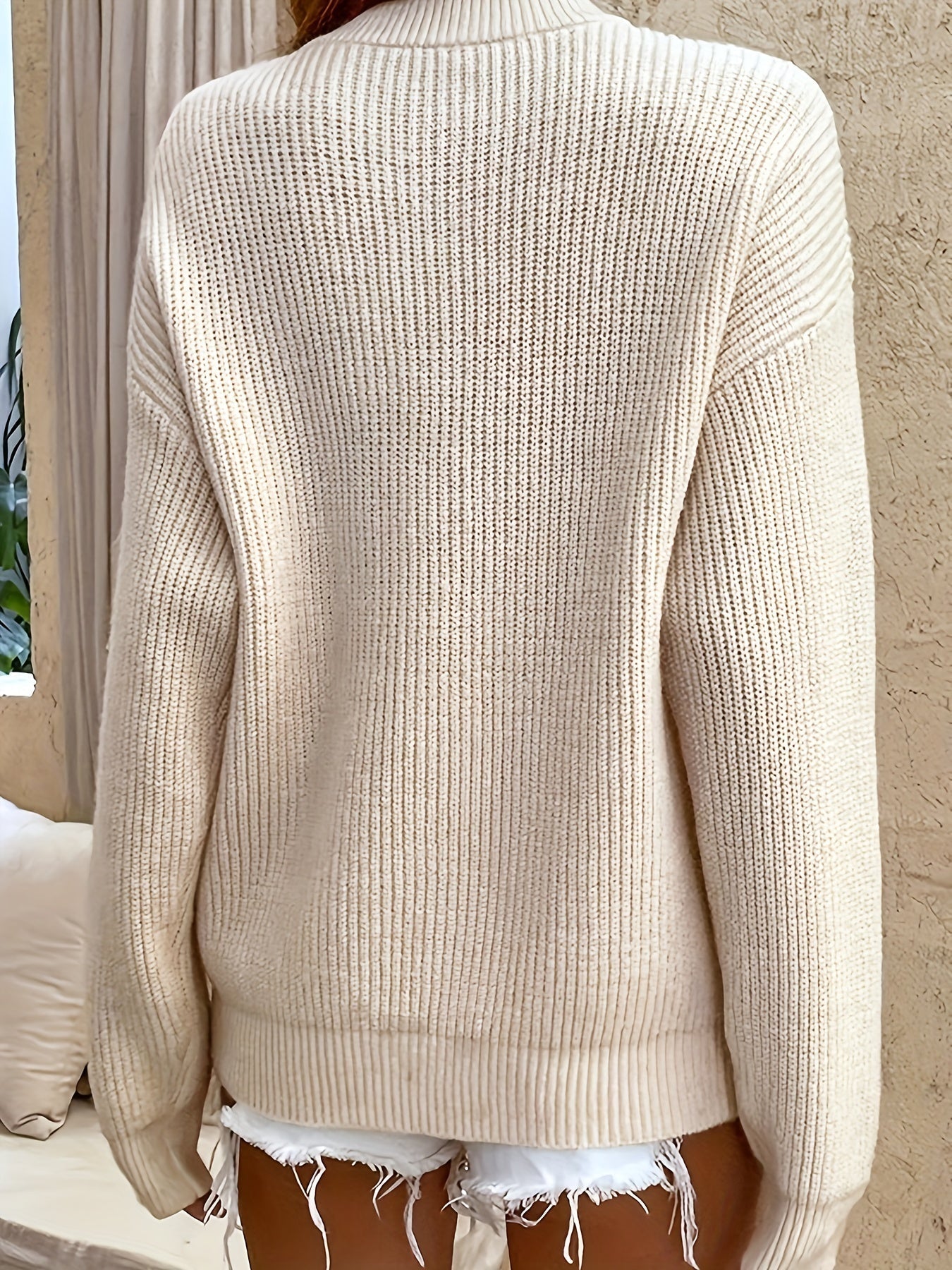 Back view of a cream ribbed knit Henley sweater with long sleeves and a relaxed fit.