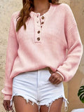 Woman wearing a pink ribbed knit Henley sweater with a button-front neckline, long sleeves, and a relaxed fit.