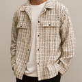 Man wearing a beige plaid overshirt jacket with a button-front closure, dual chest flap pockets, classic collar, and relaxed fit over a white T-shirt.