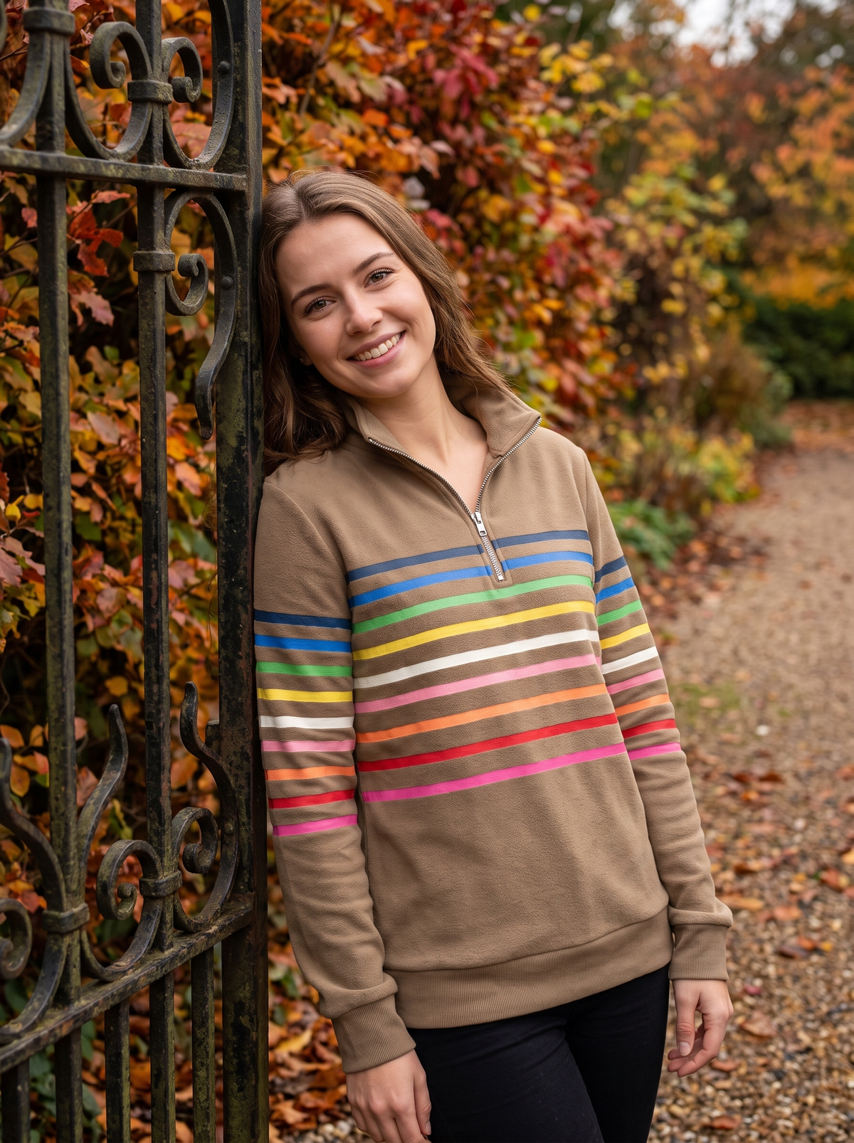 Taupe brushed cotton half-zip sweatshirt featuring vibrant horizontal stripes and a stand collar, worn outdoors.