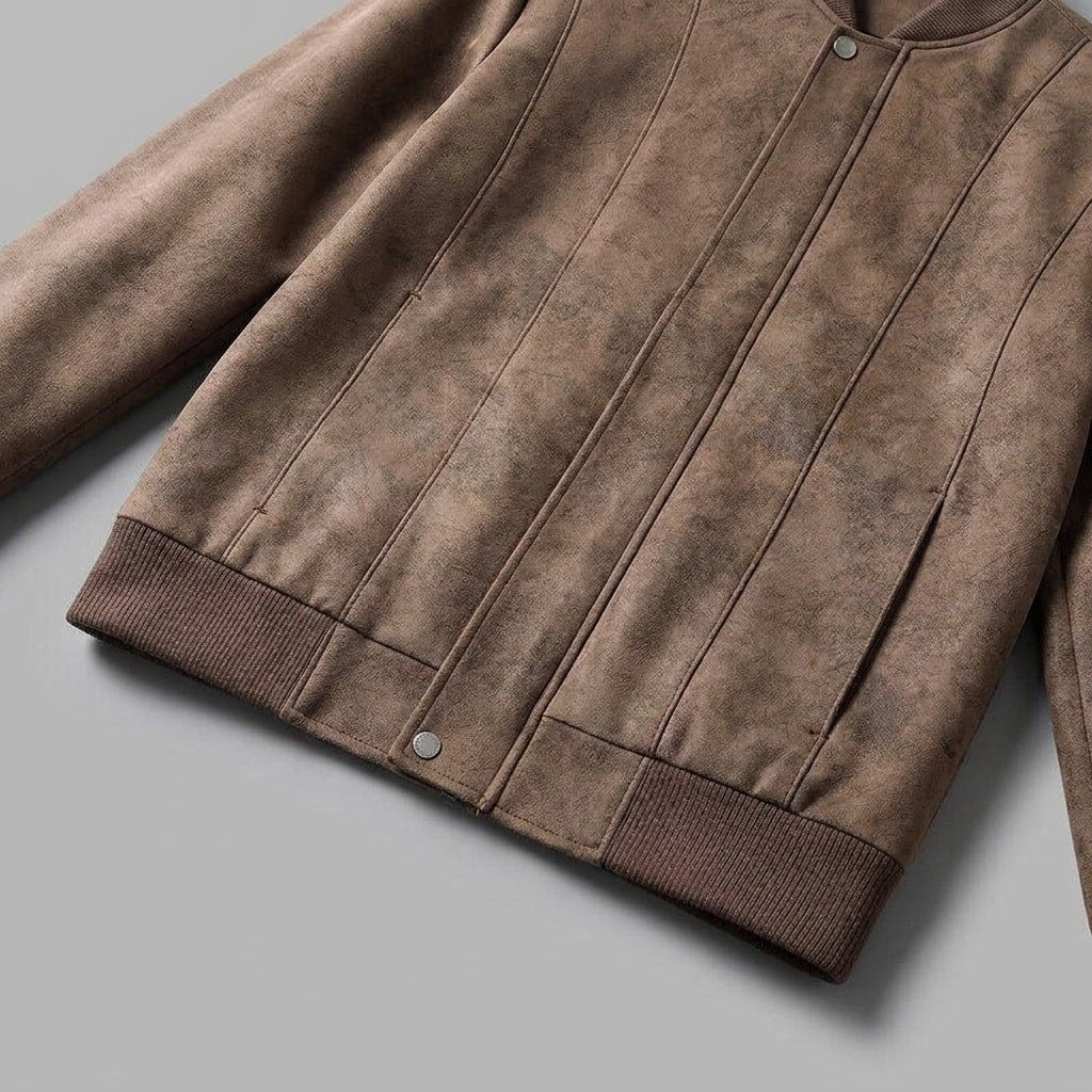 Close-up of a brown suede bomber jacket showing the textured fabric and ribbed sleeve cuff