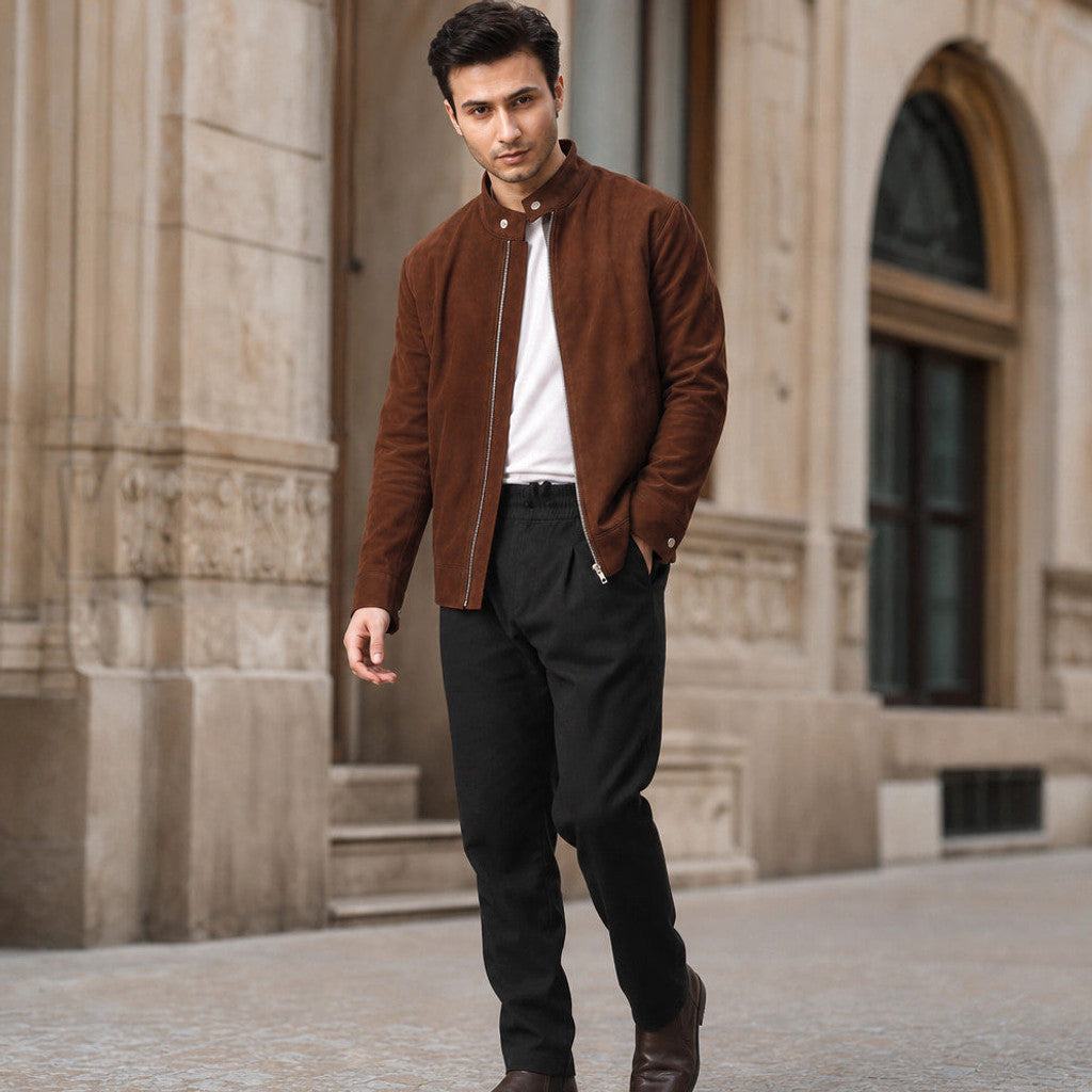 A man wearing a brown suede bomber jacket with a full-zip front and snap band collar, walking outdoors