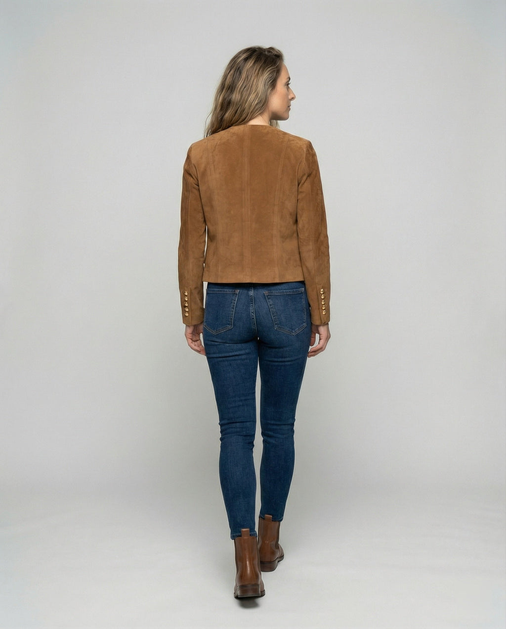 A woman wearing a brown suede cropped jacket with a collarless design, shown from the back