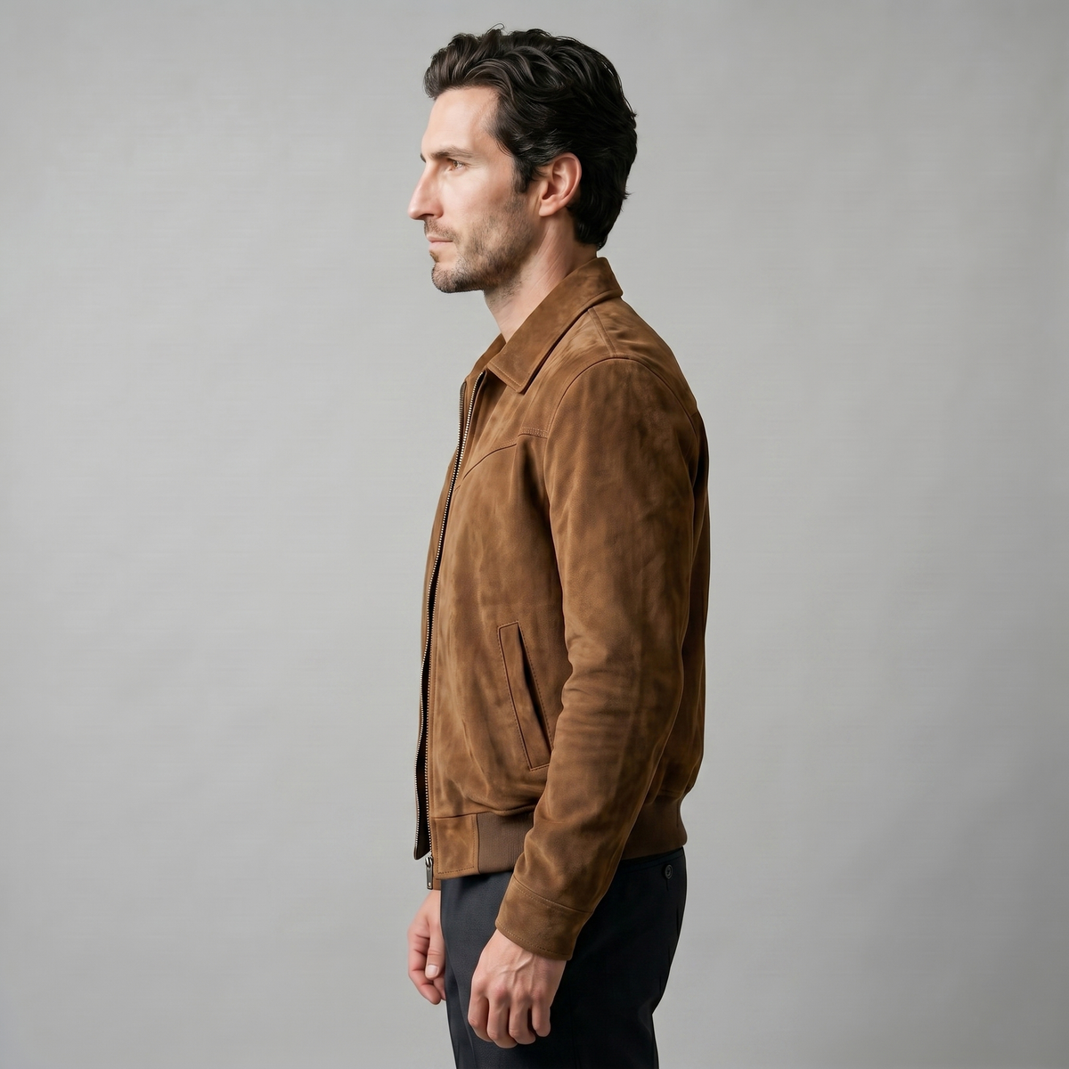 A man wearing a brown suede Harrington bomber jacket with a full-zip front and point collar, shown in side view