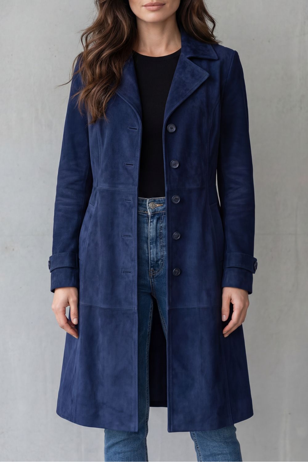 A woman wearing a blue suede longline coat with notch lapel and button-front closure