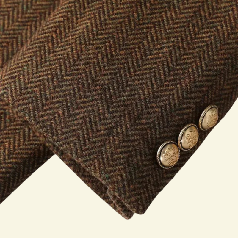 Close-up of the brown herringbone blazer sleeve showing the textured fabric and gold-tone button details.