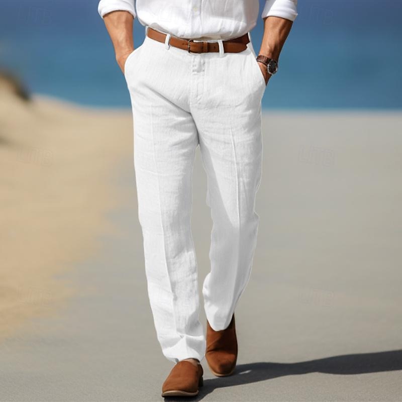 Man wearing white linen trousers with a relaxed straight-leg fit, pleated front, belt loops, and side pockets in a beachside setting.