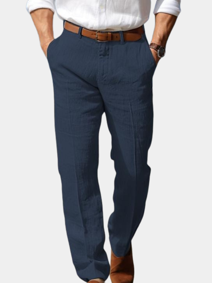 Man wearing navy linen trousers with a relaxed straight-leg fit, pleated front, and brown leather belt.