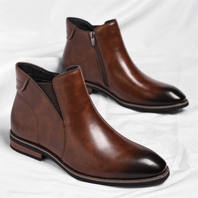 Pair of brown leather Chelsea boots with side zippers, standing together on a white sheet.